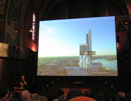 Joshua Prince-Rasmus speaking at see conference 2011 with a slide showing a model of their building for University of Louisville embedded into the city in the background