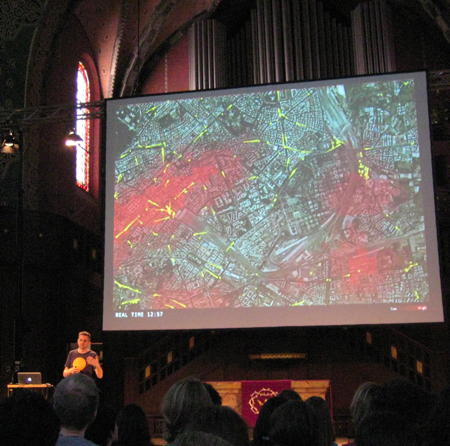 Carlo Ratti sepaking at see conference 2011 with a slide showing a map of Rome with information about mobile phone locations and bus locations in the background